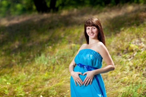 Šťastná dívka srdce na těhotné bříško — Stock fotografie