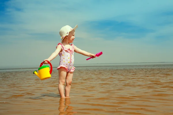 Kind met drenken-pot op de kust — Stockfoto