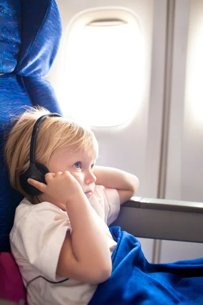 Ребенок с наушниками в самолете — стоковое фото
