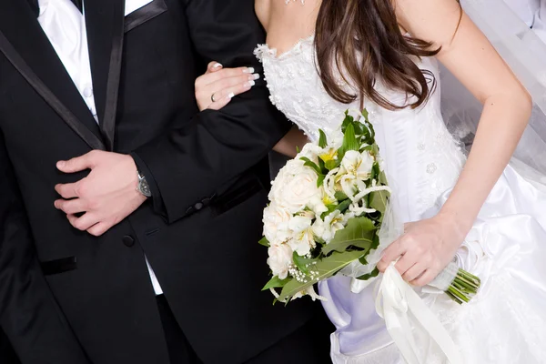 Mani di uno sposo e una sposa con un mazzo di fiori — Foto Stock