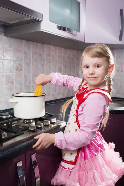 Little girl putting pasta in the pot — Stock Photo, Image