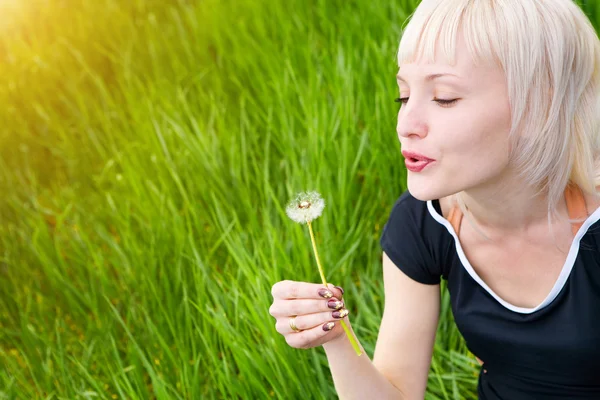 Blond meisje met witte paardebloem — Stockfoto