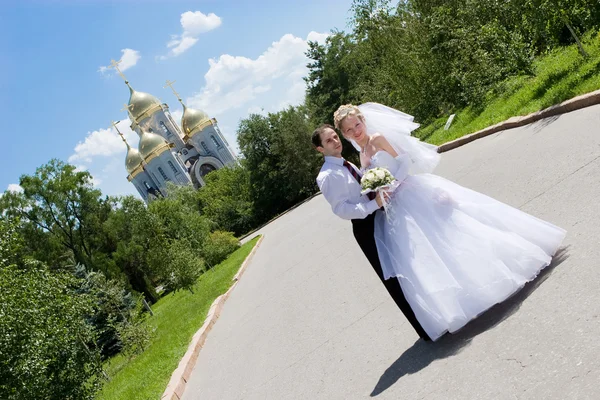 En glad brud och en brudgum nära kyrkan — Stockfoto