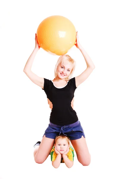 Sorridente madre e suo figlio con una palla fitness sul pavimento — Foto Stock
