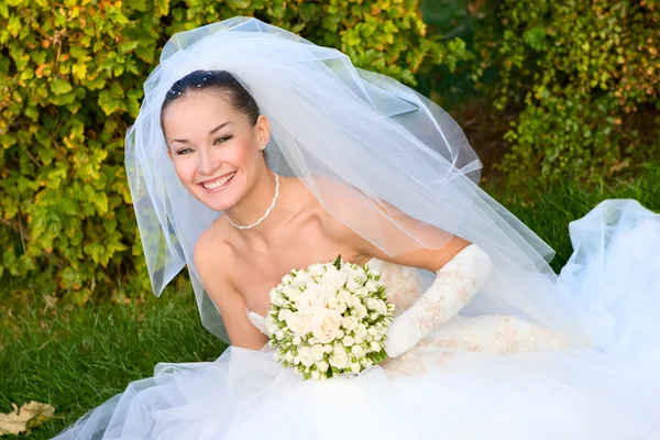 Gelukkige bruid met een bloemboeket in haar handen — Stockfoto