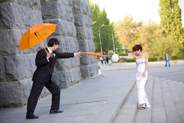 Novia y novio con paraguas naranja — Foto de Stock