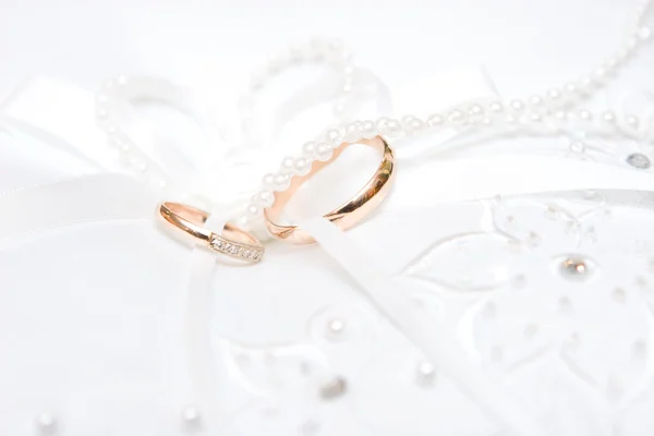 在婚纱礼服上的两个结婚戒指。 — 图库照片