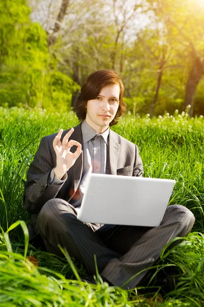 Business man with a laptop on the grass field — Stock Photo, Image