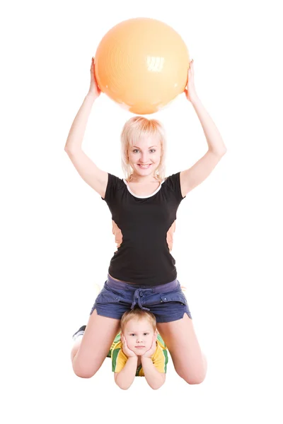 Lächelnde junge Mutter und ihr Sohn mit einem Fitnessball auf dem Parkett — Stockfoto