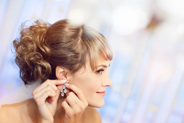 Girl puts on an earring — Stock Photo, Image