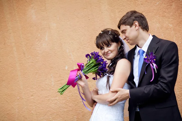 Bride and groom by the wall — Stock Photo, Image