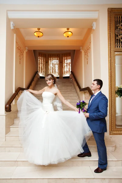 Groom and bride in hall with staircase — Stock Photo, Image