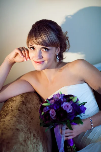 Giovane sposa con fiore sul divano — Foto Stock