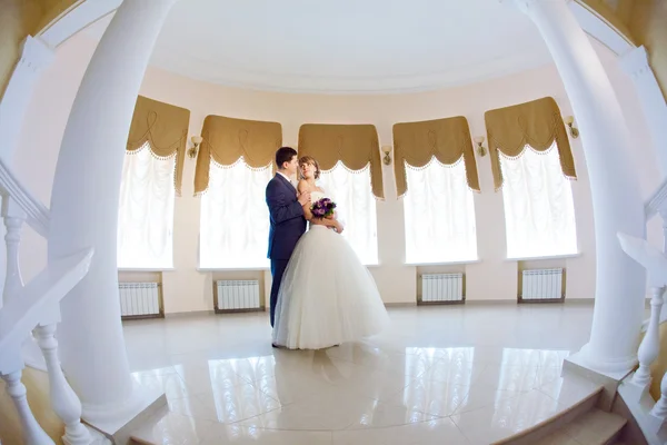 Groom and bride in hall with staircase — Stock Photo, Image