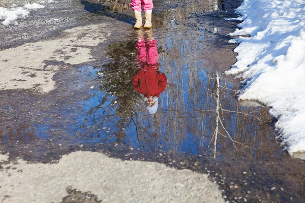 Reflexão de menina pequena na poça de primavera — Fotografia de Stock