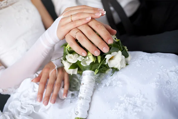 Mãos com anéis de casamento sobre o buquê — Fotografia de Stock