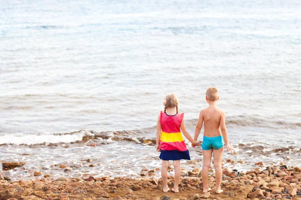 Två barn på stranden ute till havs — Stockfoto