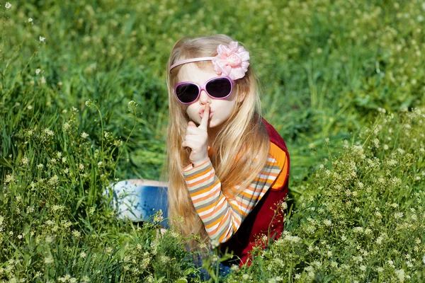 Small girl with sunglasses with fingers at lips — Stock Photo, Image