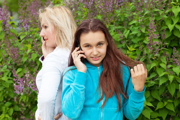 Moeder en dochter praten door telefoons Stockfoto