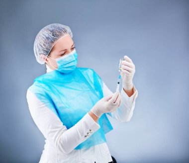 Tıp maskeli genç hemşire kameranın önünde tıbbi bir tema üzerinde poz veriyor.