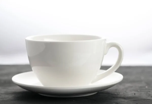 Close-up shot of a white porcelain mug on a black background — Fotografia de Stock