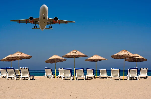 Jet flying over sunloungers on an empty beach — Stock Photo, Image