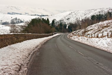 Empty road through snow covered Yorkshire moors clipart