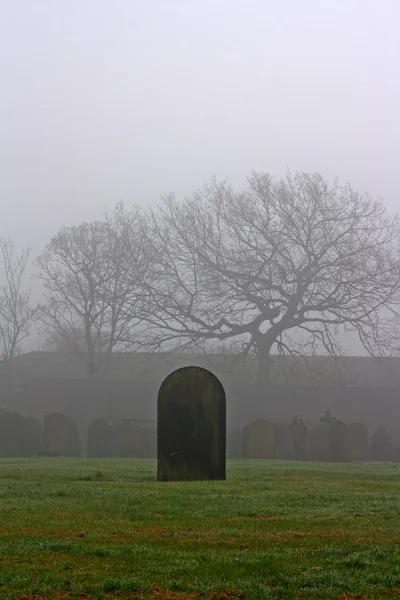 Einzelner Grabstein auf einem gruseligen Friedhof an einem nebligen Tag — Stockfoto