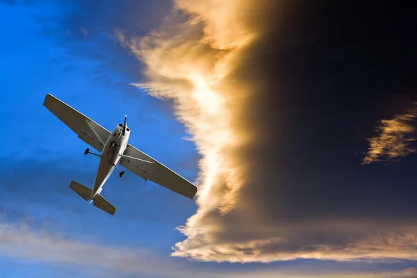 Small airplane against a stormy sunset sky — Stock Photo, Image