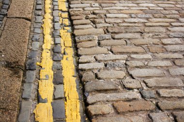 Modern (no parking) double yellow lines along ancient cobble stones clipart