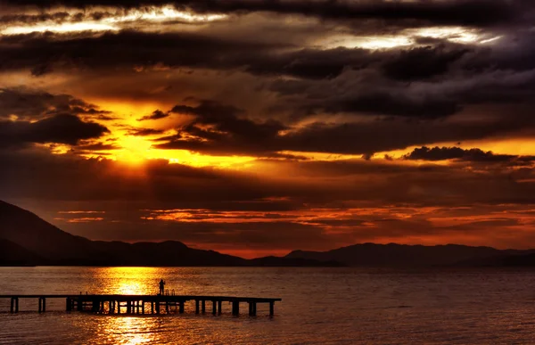 Hdr sunset with dramatic clouds and pier — Stock Photo, Image