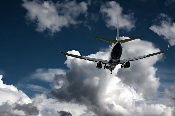 Jet passeggeri atterraggio contro un cielo blu con bianco soffice nuvola — Foto Stock