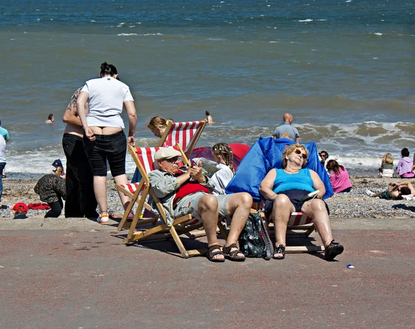 Pensionärer sitter på solstolar på brittiska seaside resort — Stockfoto