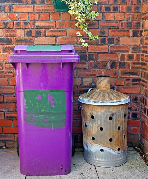 Колесная корзина и садовый мусоросжигатель против кирпичной стены — стоковое фото
