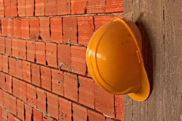 Construction workers yellow hard hat hanging on concrete wall — Stock Photo, Image