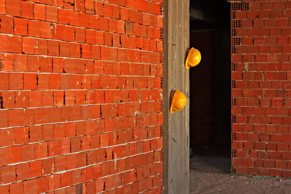 Lavoratori edili cappelli duri gialli appesi al muro di cemento — Foto Stock