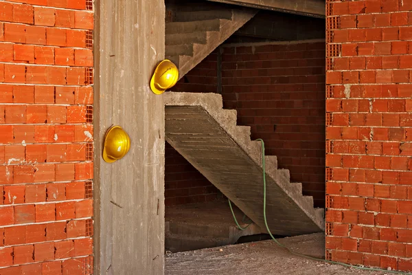 Travailleurs de la construction chapeaux durs jaunes accrochés au mur de béton — Photo