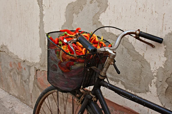 Bicicleta enferrujada velha com pimentas coloridas na cesta — Fotografia de Stock