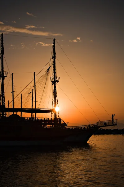 Sailing ship silhouetted against amber setting sun — Stock Photo, Image