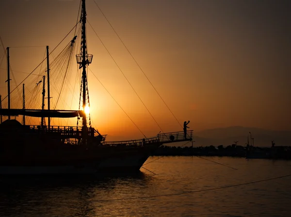 Sailing ship silhouetted against amber setting sun — Stock Photo, Image