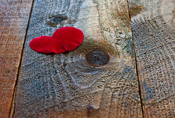 Pétalo de rosa en forma de corazón rojo sobre mesa de madera rústica —  Fotos de Stock