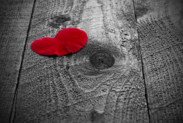 Coração vermelho em forma de pétala de rosa na mesa de madeira rústica — Fotografia de Stock