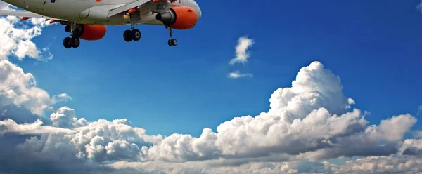 Jet de pasajeros contra un cielo azul con nubes blancas esponjosas —  Fotos de Stock