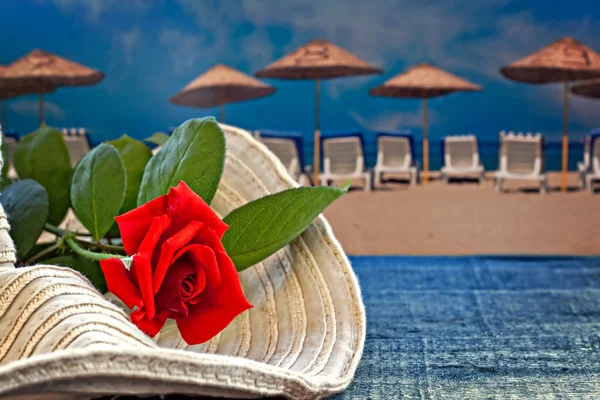 Womans summer hat with red rose with empty beach — Stock Photo, Image