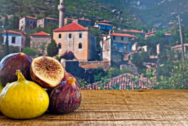 Fresh figs on rustic wooden table against village background — Stock Photo, Image