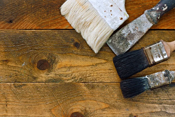 Używane farby, szczoteczki oraz odcinającego na starym drewnianym stole — Zdjęcie stockowe