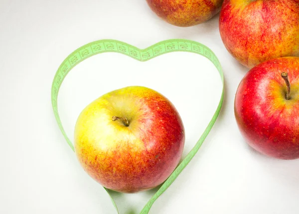 Czerwone jabłka z Miara zwijana, tworząc kształt serca — Zdjęcie stockowe