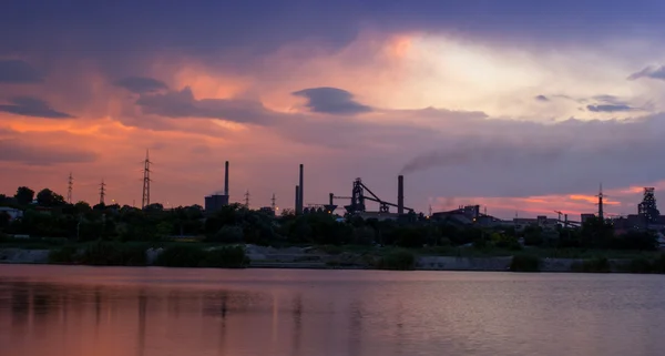 Silhouette of industrial factory at sunset mirror in water — Stock Photo, Image