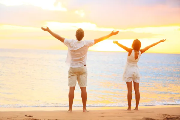 Feliz pareja animadora disfrutando de la puesta de sol en la playa —  Fotos de Stock