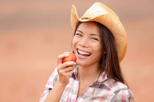 Amerykański cowgirl jedzenie brzoskwinia uśmiechający się zadowolony — Zdjęcie stockowe